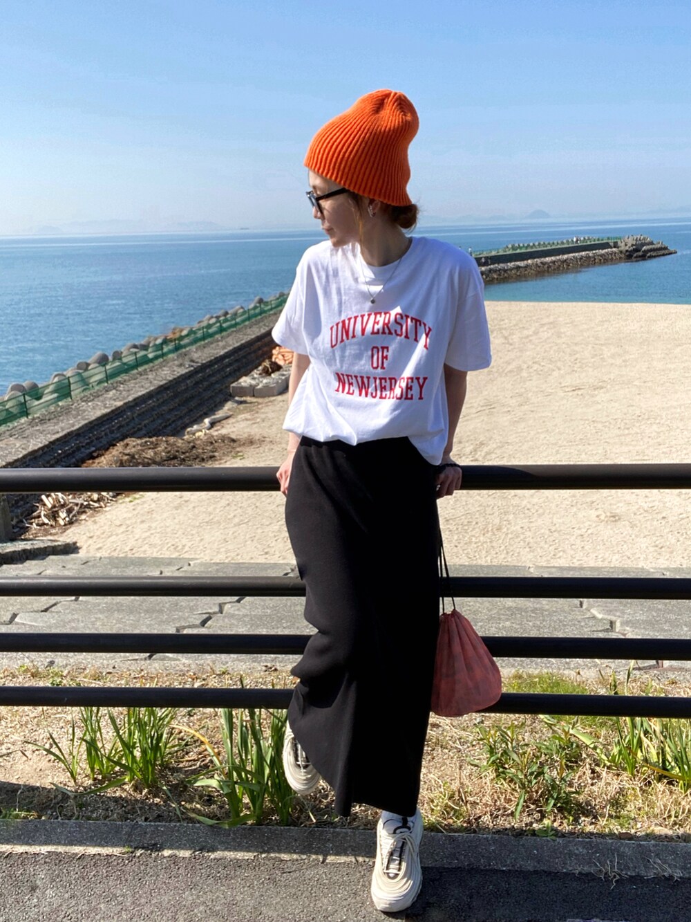 ホワイト系のTシャツ/カットソー、ブラック系のスカート、ホワイト系のスニーカーを着用したレディースの春コーディネートの2枚目の写真