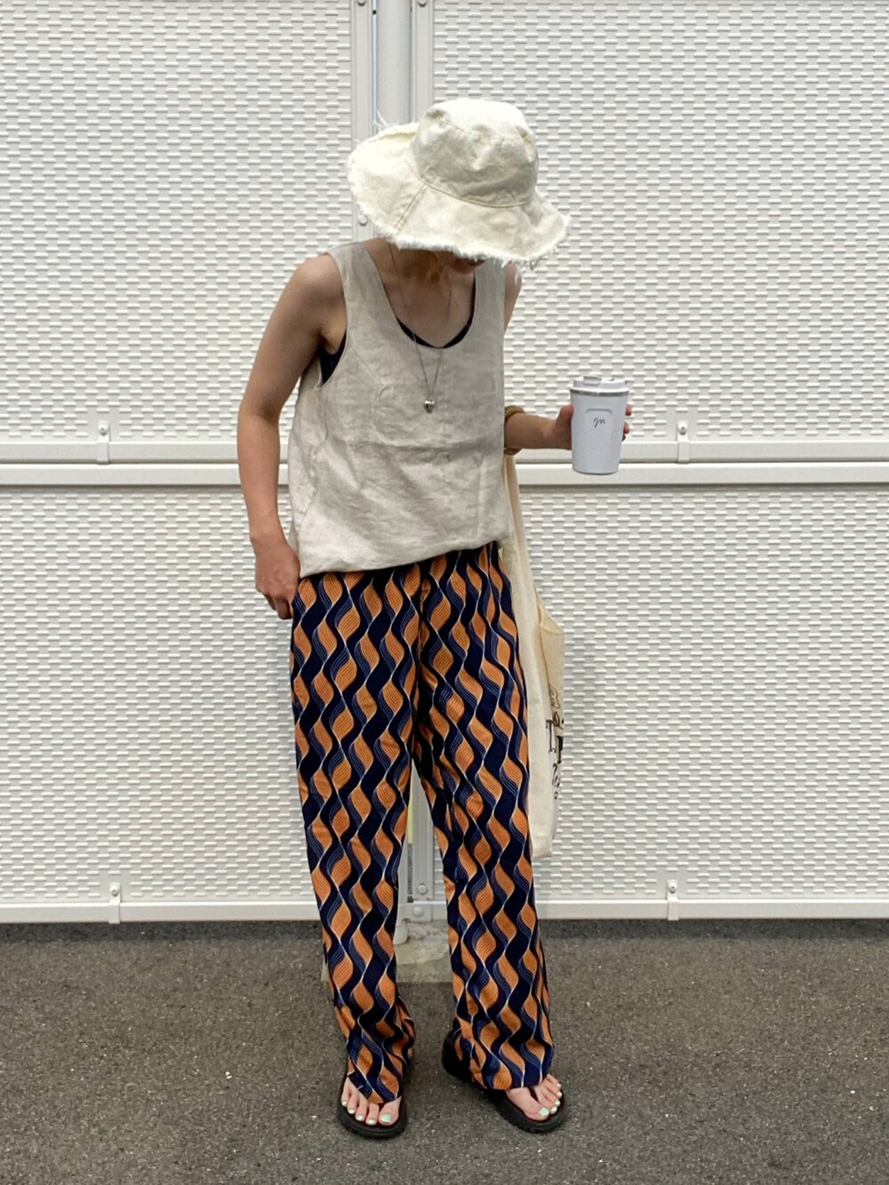 ブルー系のその他パンツ、ベージュ系のタンクトップ、その他のエコバッグ/サブバッグを着用したレディースの夏コーディネートの3枚目の写真