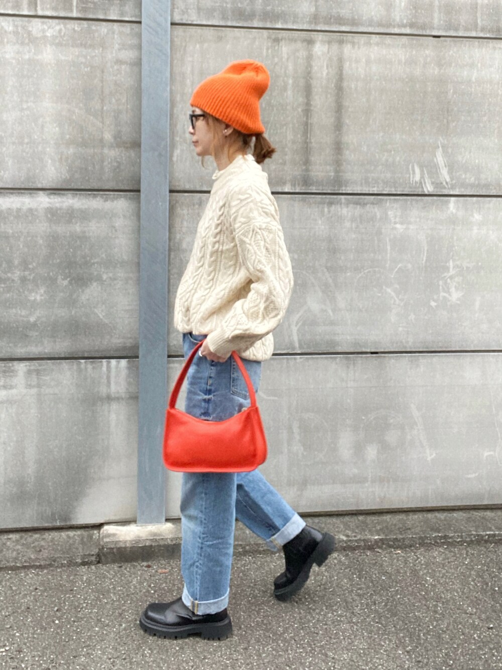 ホワイト系のニット/セーター、オレンジ系のショルダーバッグ、ブラック系のブーツを着用したレディースの冬コーディネートの2枚目の写真