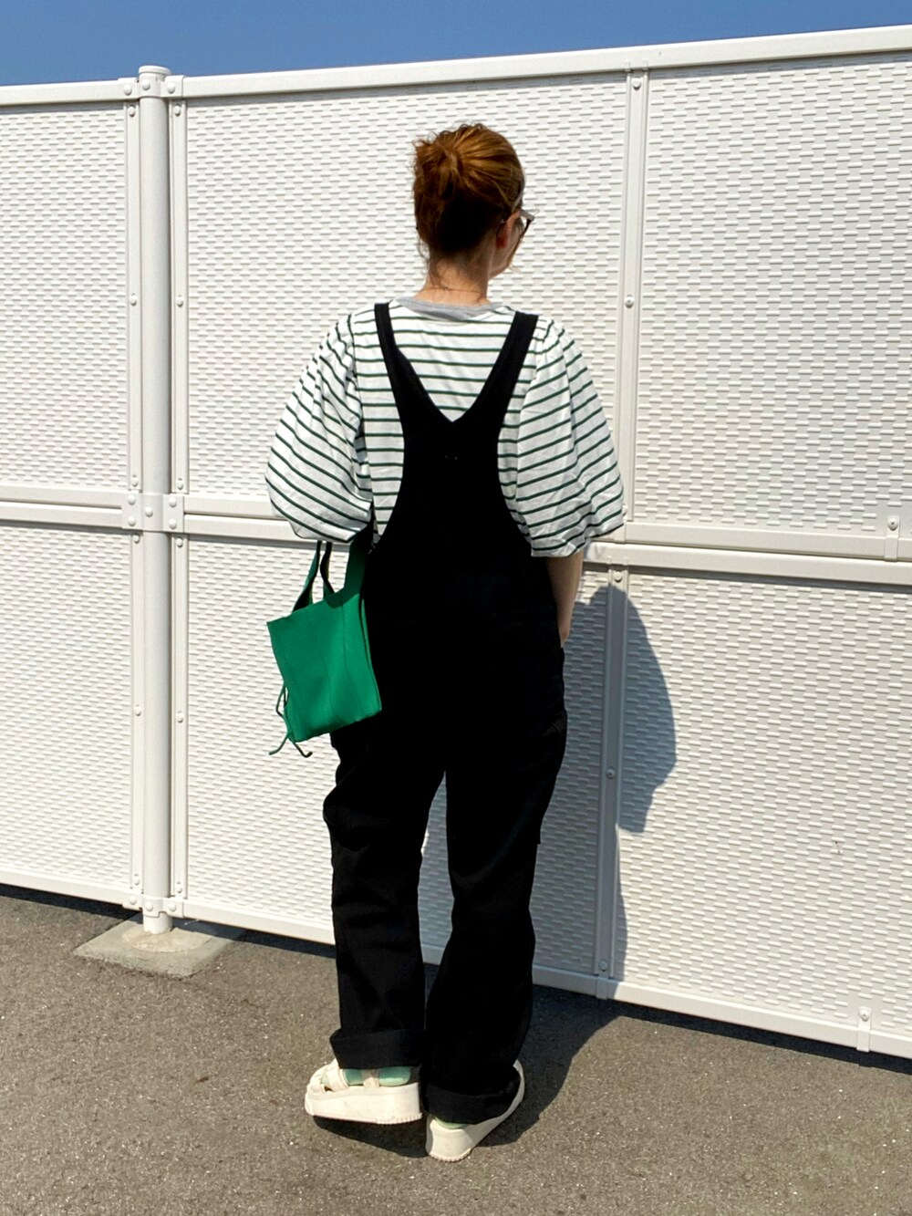 ブラック系のサロペット/オーバーオール、グリーン系のTシャツ/カットソー、ベージュ系のサンダルを着用したレディースの春コーディネートの2枚目の写真