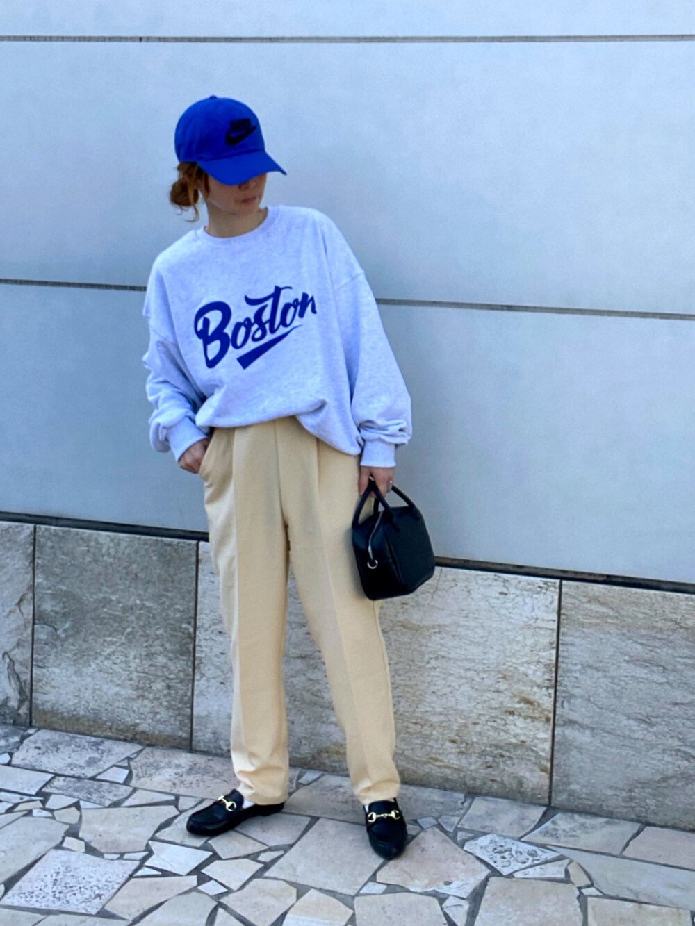 イエロー系のスラックス、ブラック系のボストンバッグ、ブラック系のローファーを着用したレディースの春コーディネートの2枚目の写真