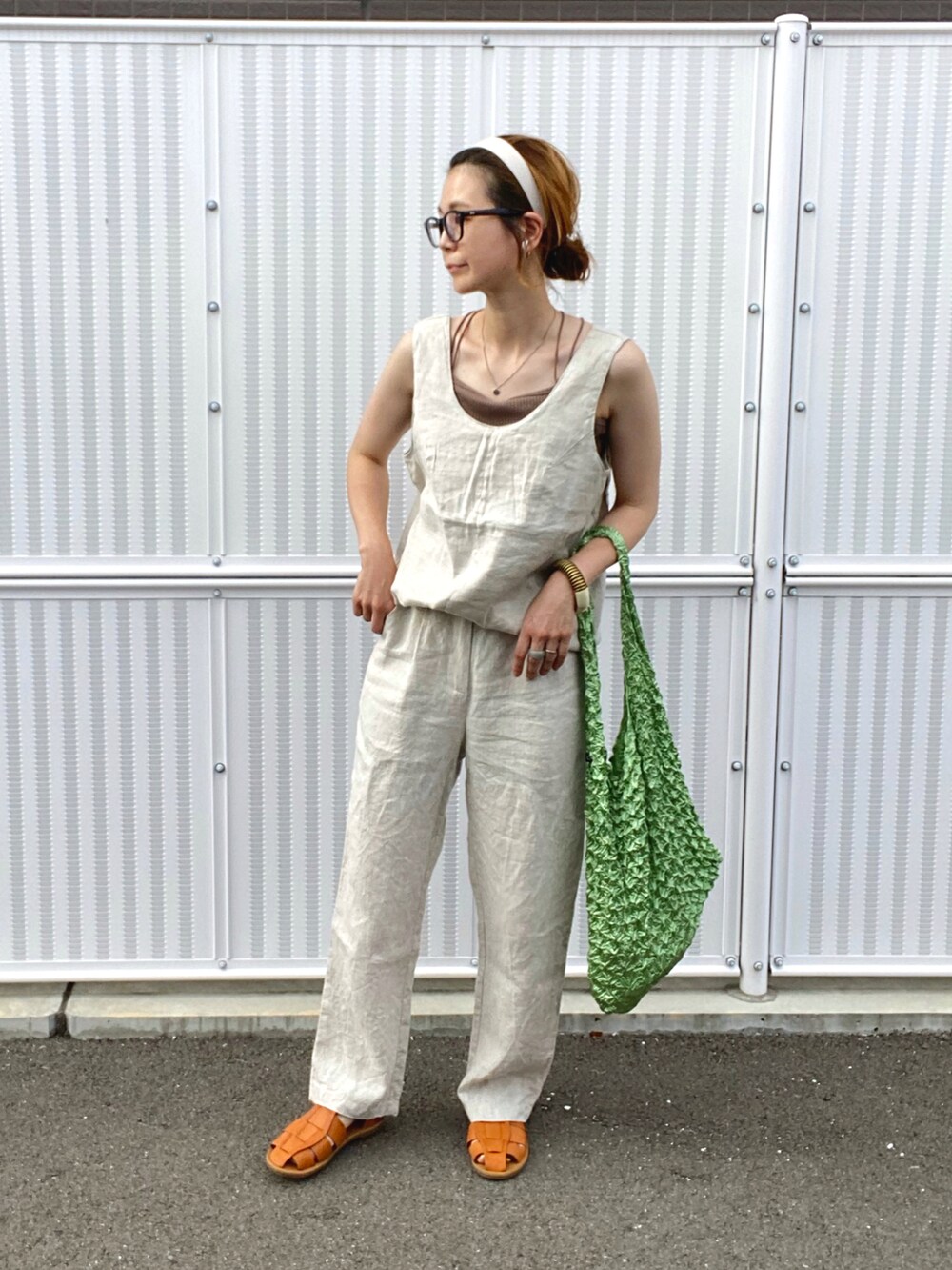 ベージュ系のタンクトップ、ブラウン系のキャミソール、ベージュ系のスラックスを着用したレディースの夏コーディネートの3枚目の写真