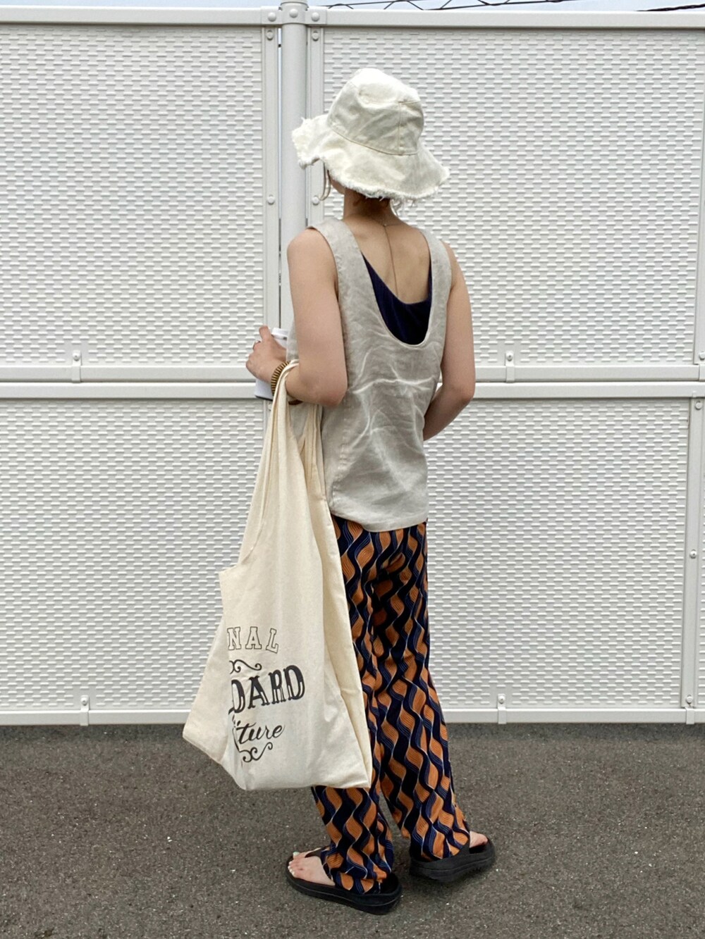 ブルー系のその他パンツ、ベージュ系のタンクトップ、その他のエコバッグ/サブバッグを着用したレディースの夏コーディネートの2枚目の写真