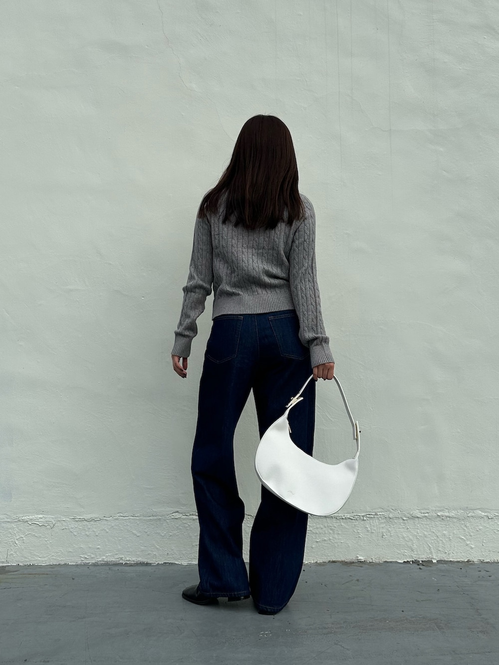 ブラック系のデニムパンツを着用したレディースの秋コーディネートの2枚目の写真