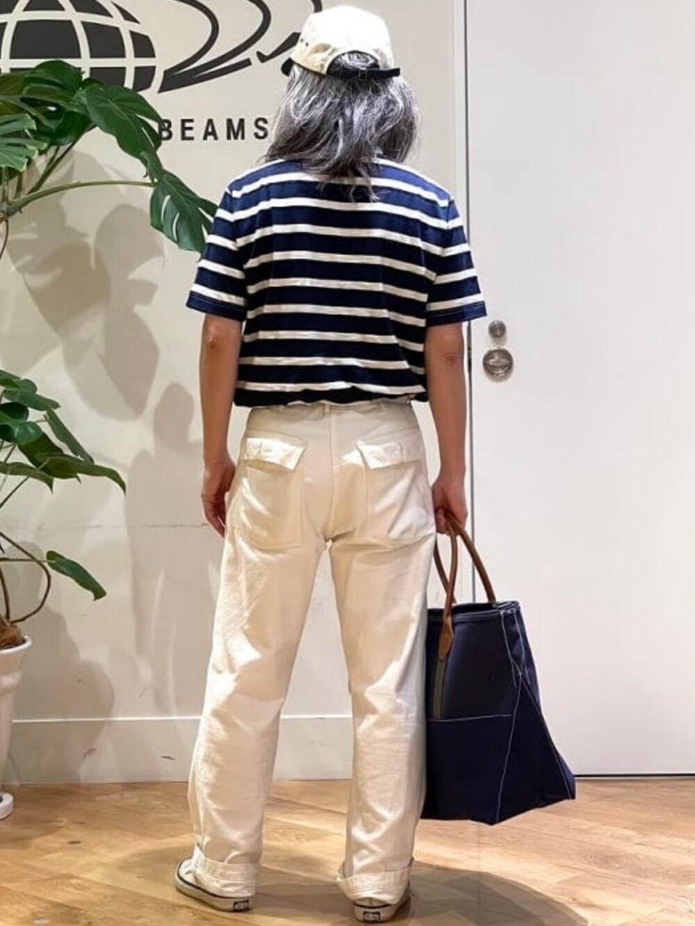 ブルー系のトートバッグ、ブルー系のTシャツ/カットソー、ホワイト系のキャップを着用したメンズの夏コーディネートの2枚目の写真