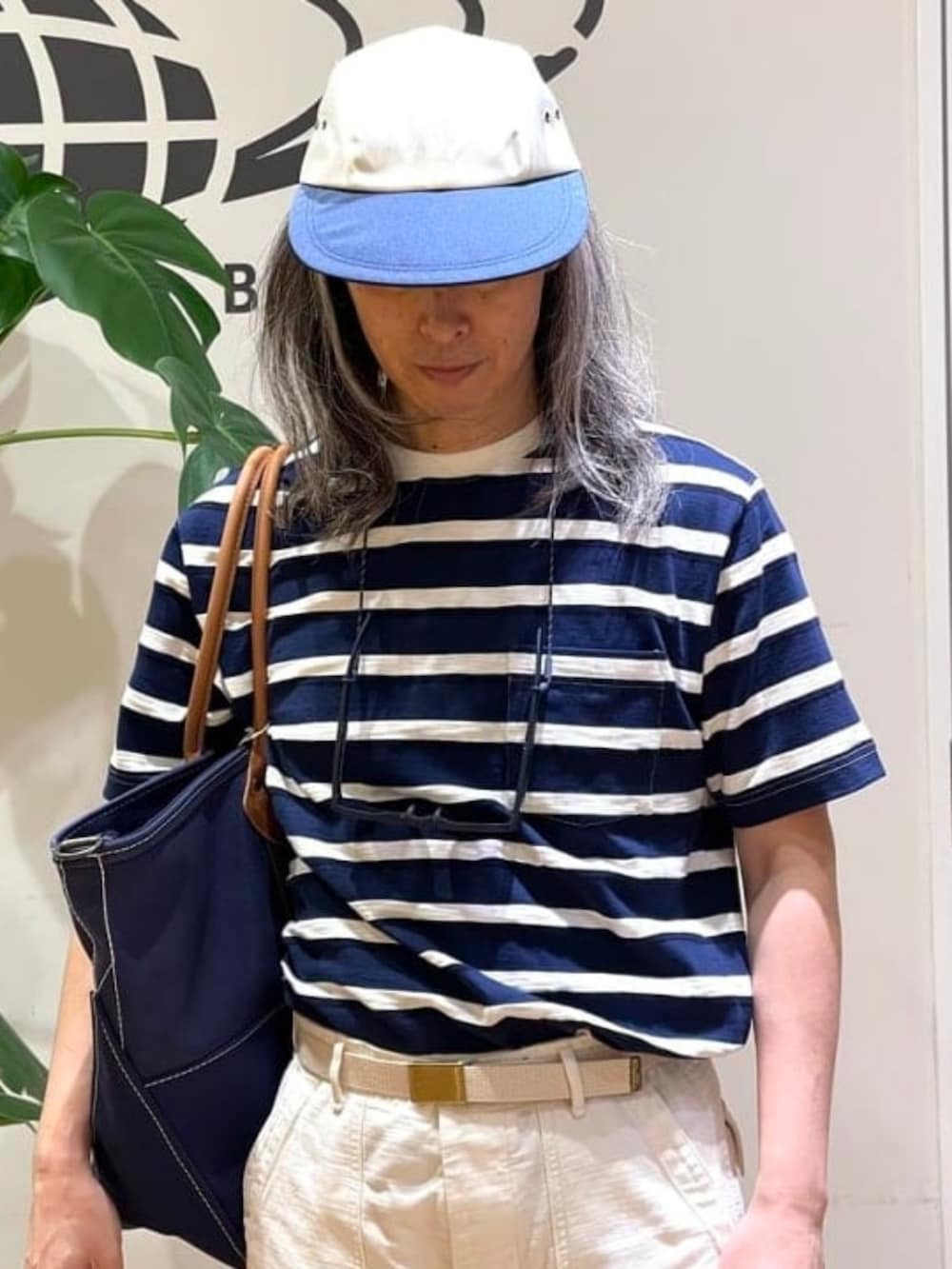 ブルー系のトートバッグ、ブルー系のTシャツ/カットソー、ホワイト系のキャップを着用したメンズの夏コーディネートの3枚目の写真