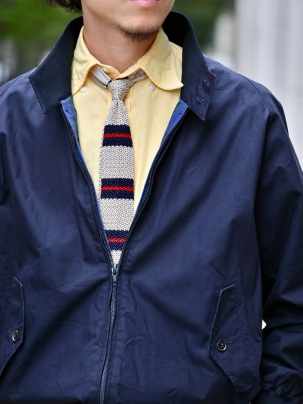 グリーン系のチノパンツ、ブルー系のブルゾン、ホワイト系のネクタイを着用したメンズの秋コーディネートの2枚目の写真