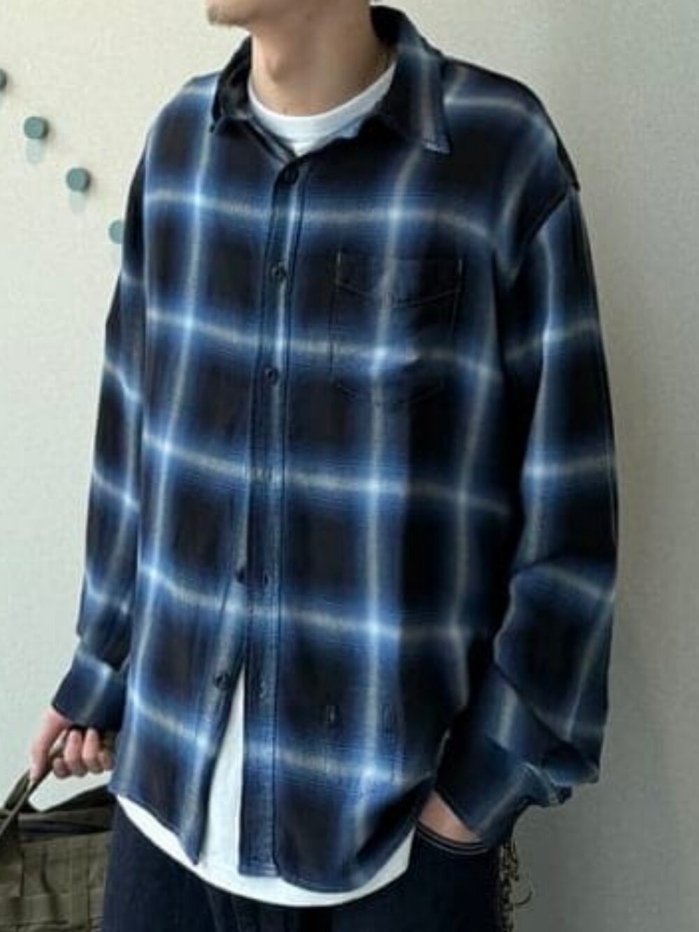 ブラック系のシャツ/ブラウス、グリーン系のトートバッグ、ブルー系のデニムパンツを着用したメンズの春コーディネートの3枚目の写真