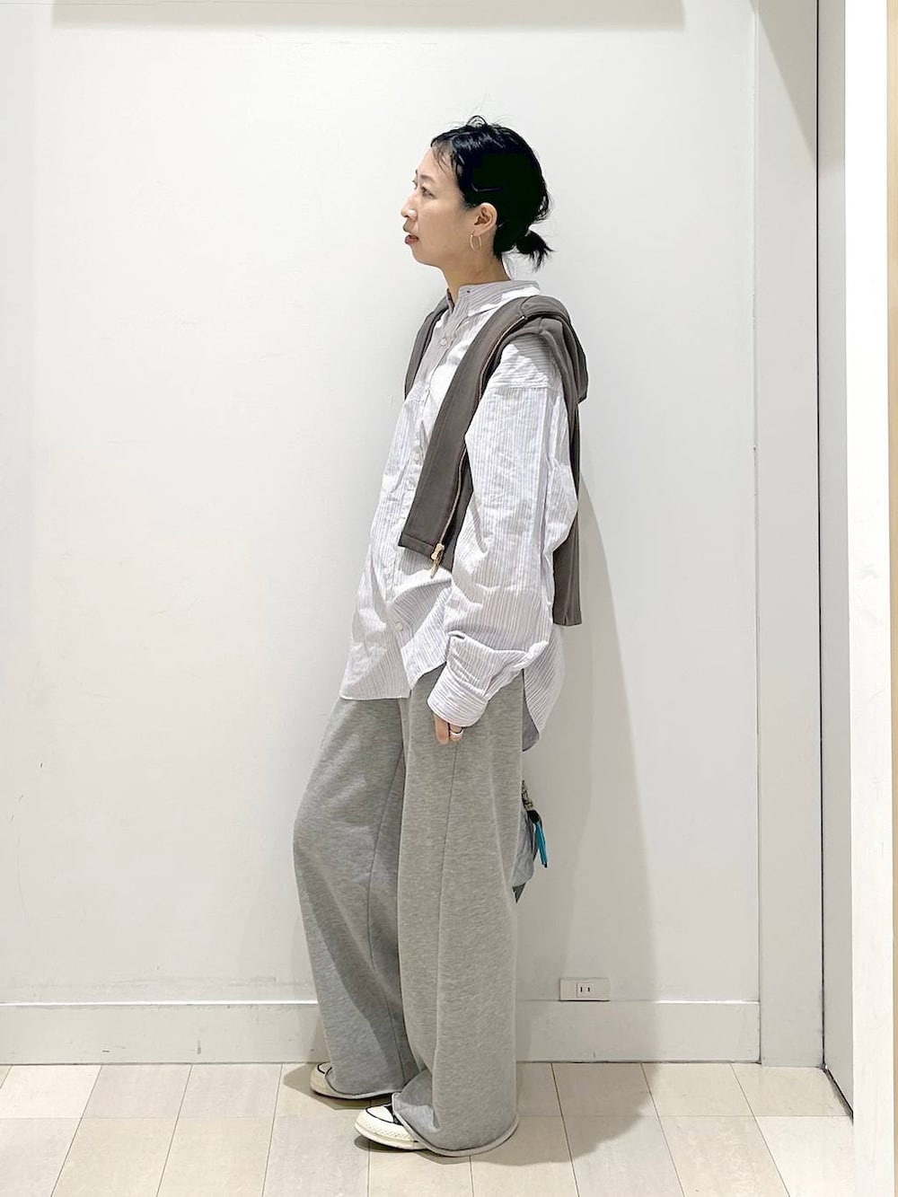 シルバー系のハンドバッグ、グレー系のスウェットパンツ、ブラウン系のベストを着用したレディースの春コーディネートの4枚目の写真