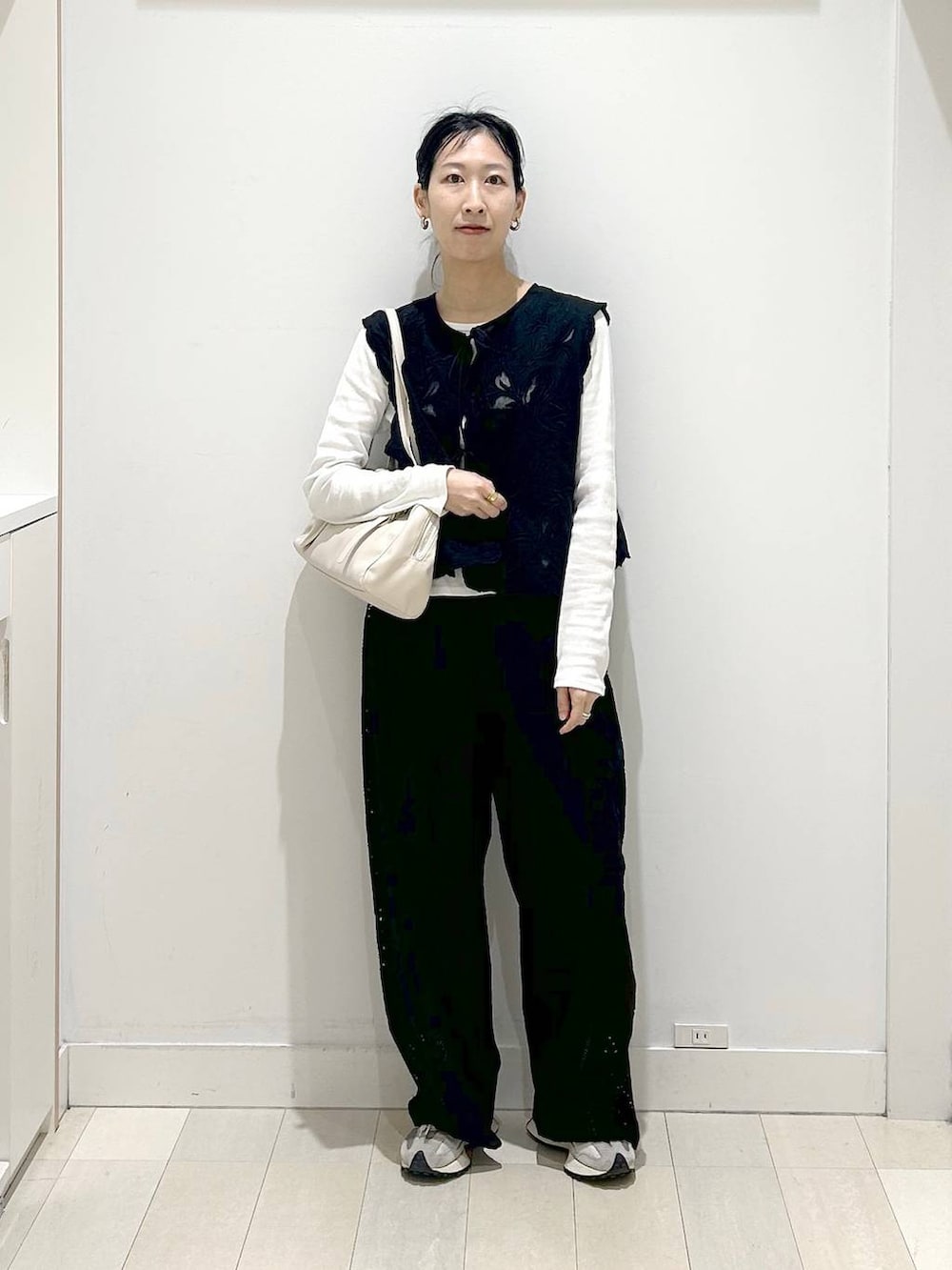 ブラック系のベスト、ブラック系のその他パンツ、ベージュ系のショルダーバッグを着用したレディースの春コーディネートの5枚目の写真