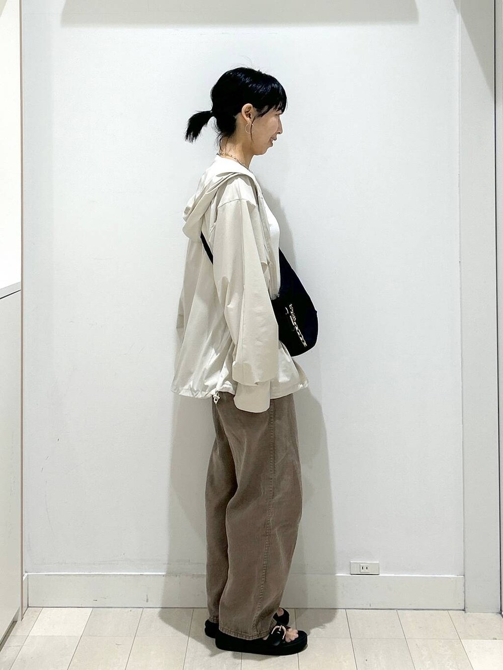 ブラック系のショルダーバッグ、ブラウン系のデニムパンツ、ベージュ系のマウンテンパーカーを着用したレディースの夏コーディネートの2枚目の写真