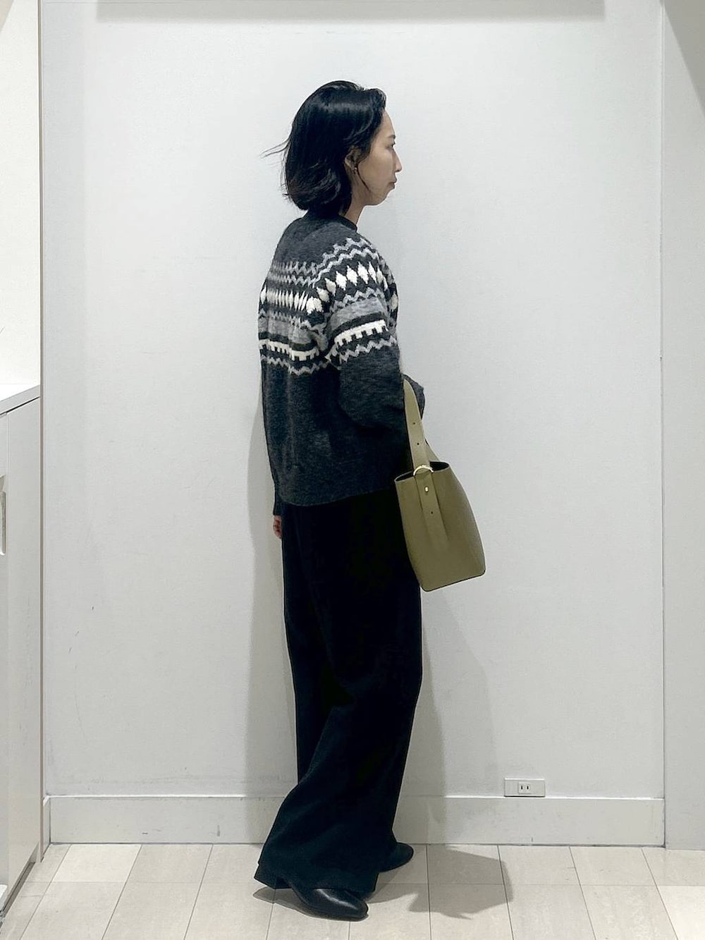 グリーン系のショルダーバッグ、グレー系のニット/セーター、ブラック系のその他パンツを着用したレディースの冬コーディネートの2枚目の写真