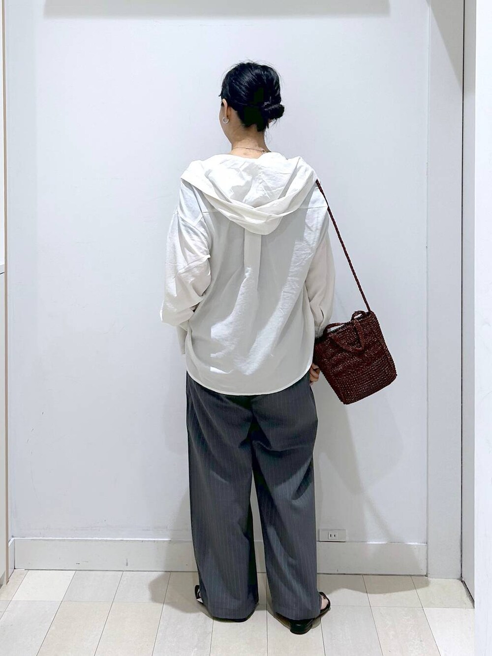 グレー系のその他パンツ、ホワイト系のTシャツ/カットソー、ブラウン系のクラッチバッグを着用したレディースの夏コーディネートの3枚目の写真