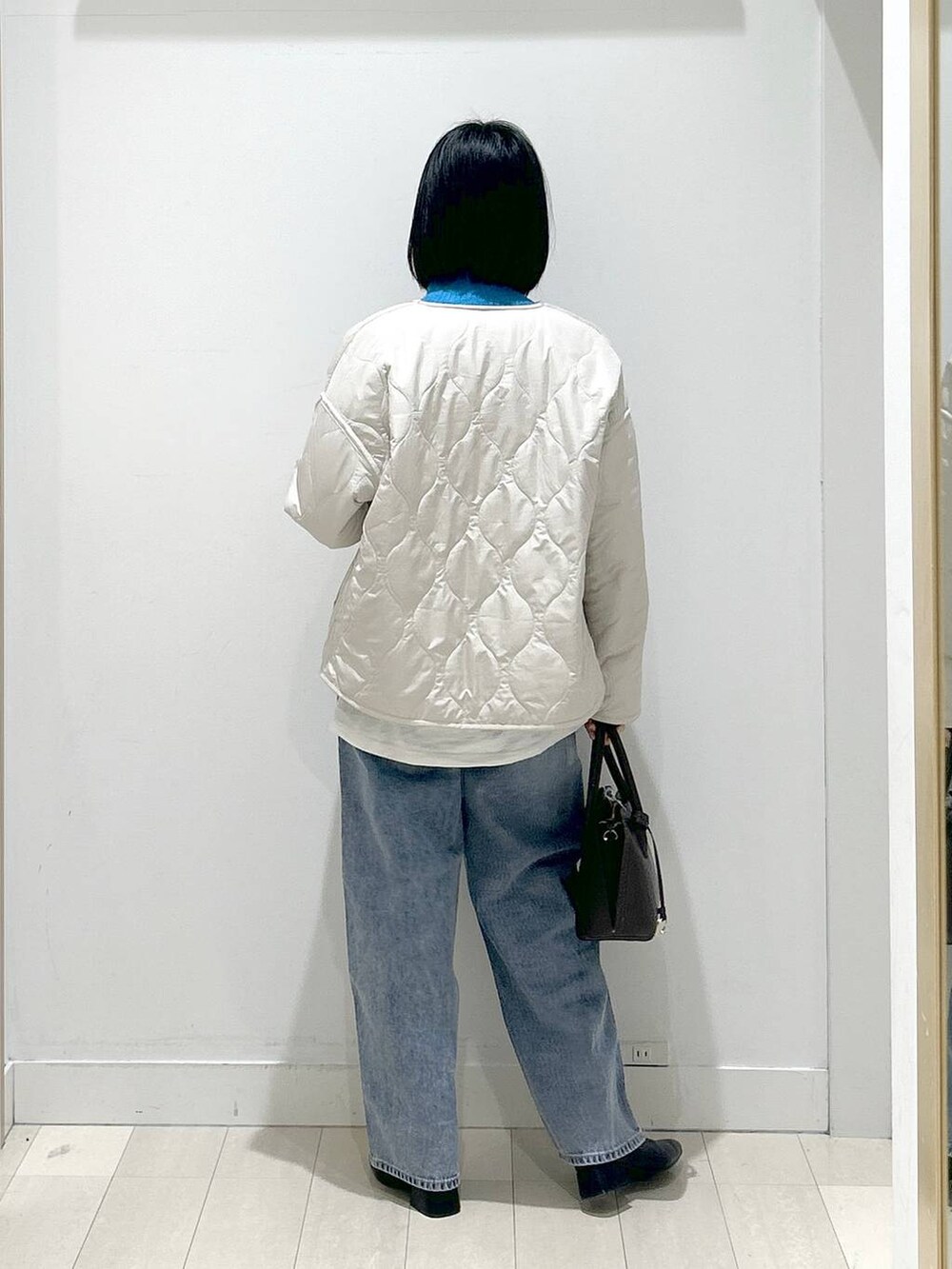 ブラウン系のショルダーバッグ、ベージュ系のブルゾン、ブルー系のデニムパンツを着用したレディースの冬コーディネートの3枚目の写真