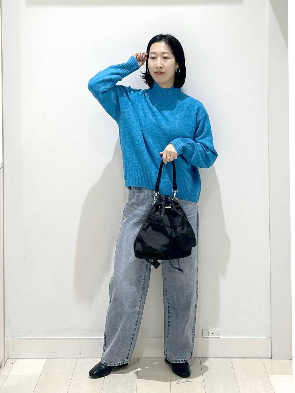 ブラック系のショルダーバッグ、ブルー系のデニムパンツ、ブラック系のブーツを着用したレディースの冬コーディネートの5枚目の写真