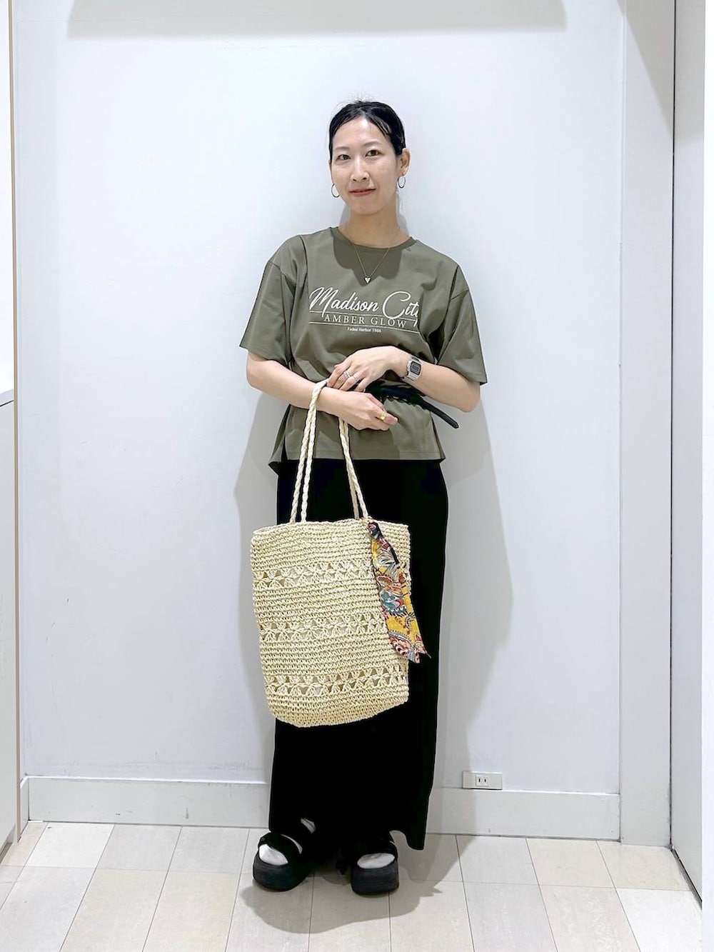 グリーン系のTシャツ/カットソー、ベージュ系のトートバッグ、ブラック系のスカートを着用したレディースの夏コーディネートの5枚目の写真