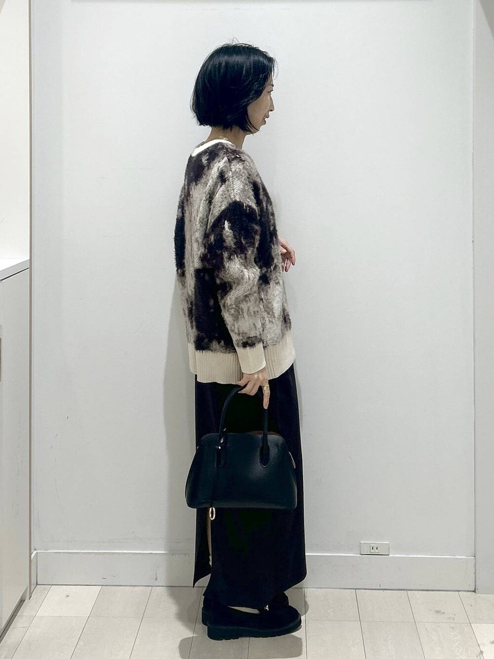 ブラック系のショルダーバッグ、ブラック系のローファー、ホワイト系のTシャツ/カットソーを着用したレディースの秋コーディネートの2枚目の写真