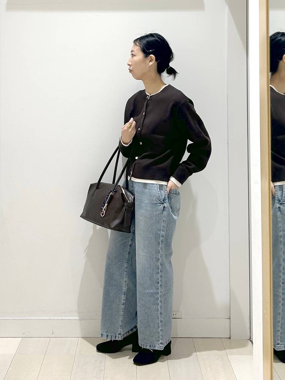 ブラック系のローファー、ブラック系のボストンバッグ、ブルー系のデニムパンツを着用したレディースの春コーディネートの4枚目の写真