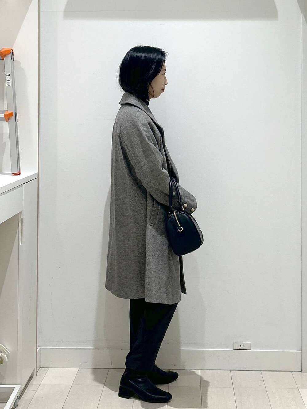 ブラウン系のチェスターコート、グレー系のその他パンツ、グレー系のニット/セーターを着用したレディースの冬コーディネートの2枚目の写真