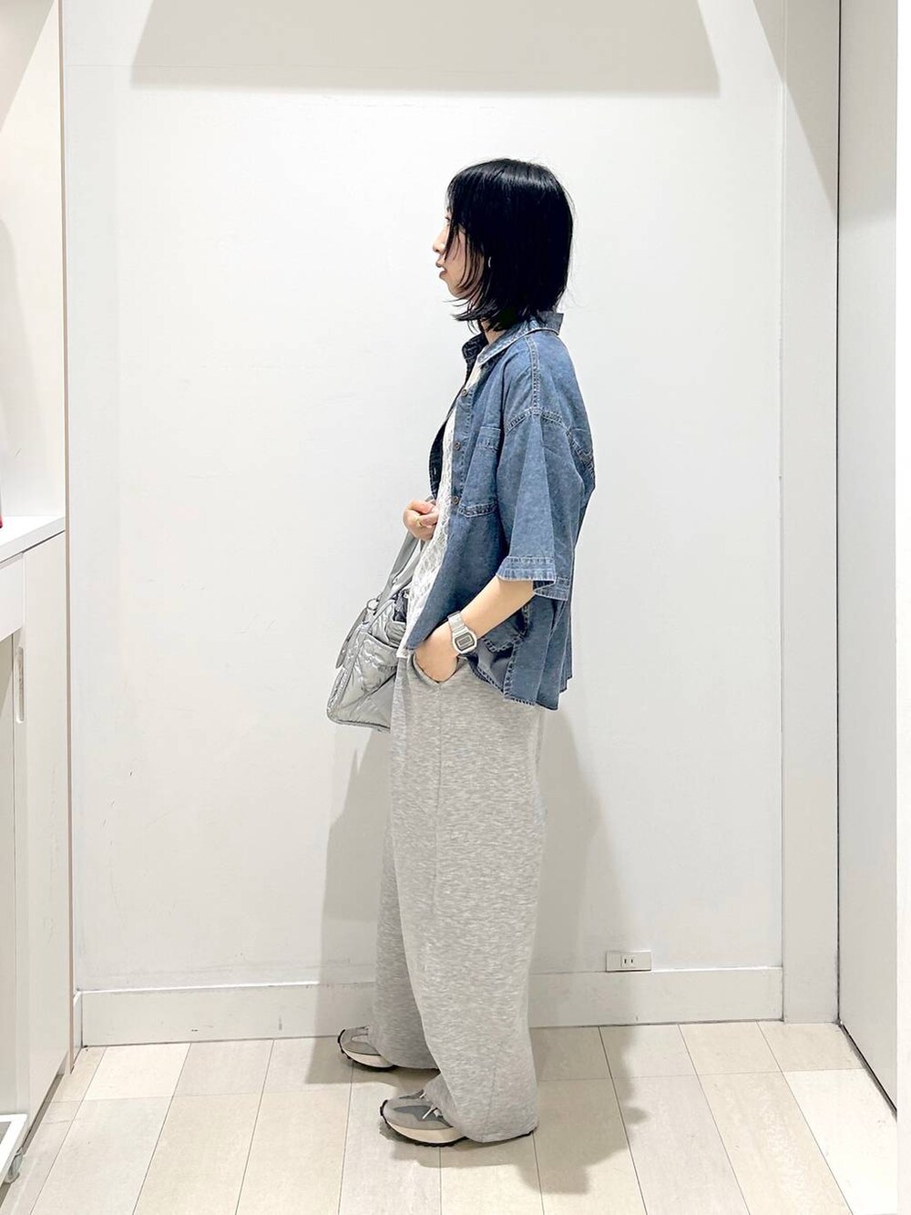 シルバー系のトートバッグ、ホワイト系のTシャツ/カットソー、ブルー系のシャツ/ブラウスを着用したレディースの春コーディネートの2枚目の写真