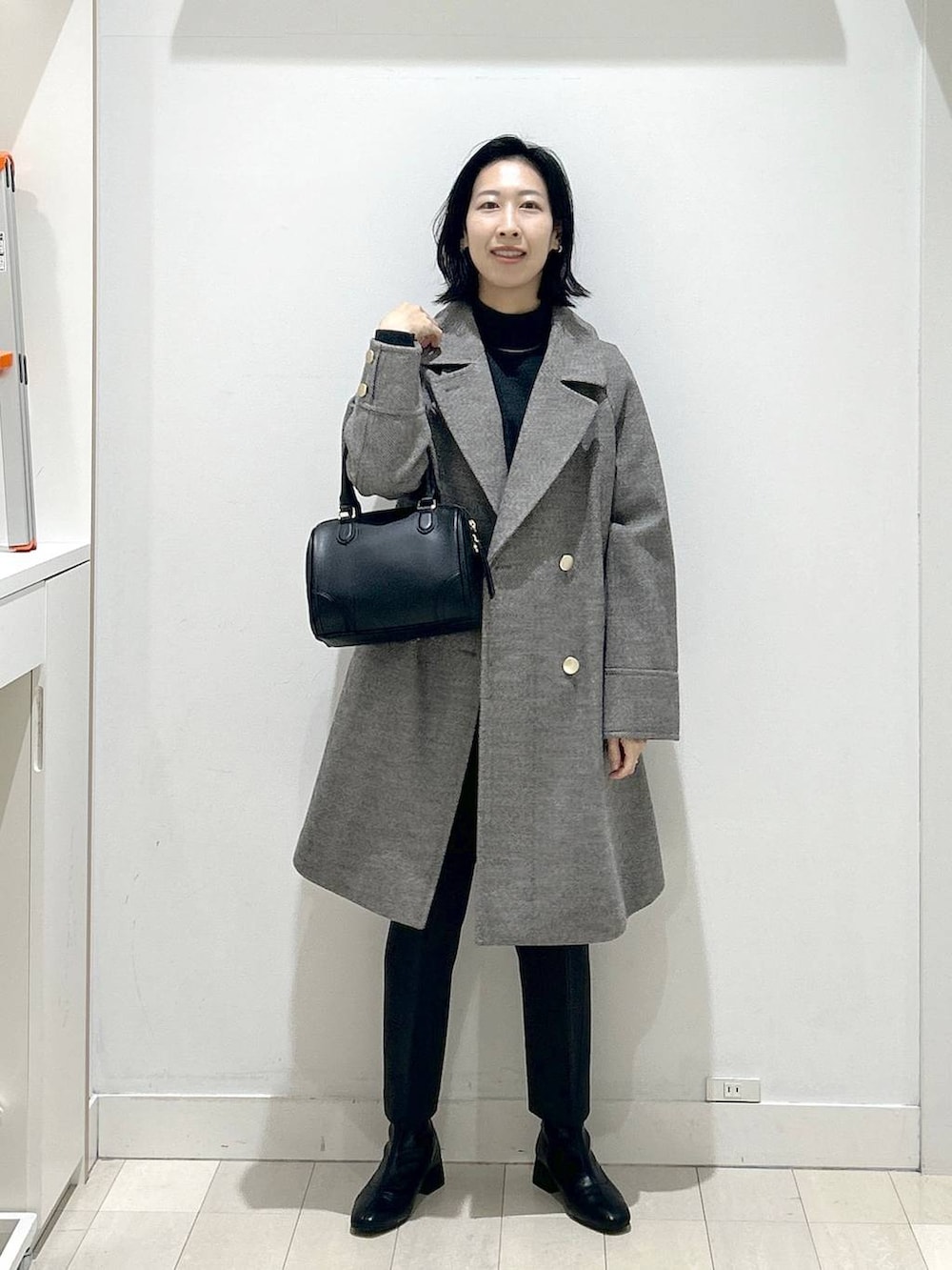 ブラウン系のチェスターコート、グレー系のその他パンツ、グレー系のニット/セーターを着用したレディースの冬コーディネートの5枚目の写真