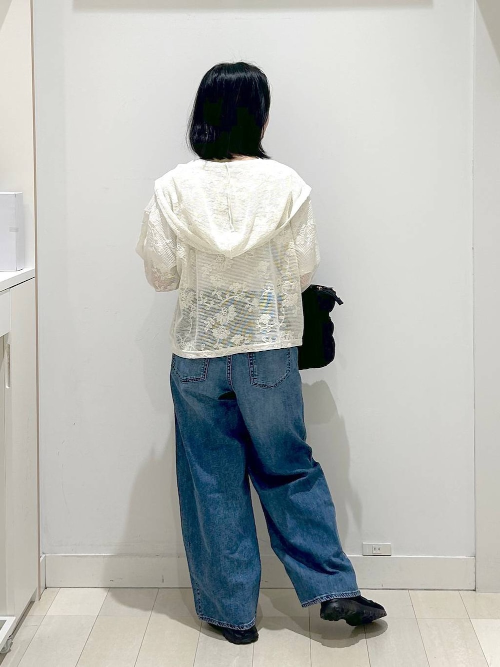 ブラック系のトートバッグ、ブルー系のデニムパンツ、ベージュ系のパーカーを着用したレディースの春コーディネートの3枚目の写真