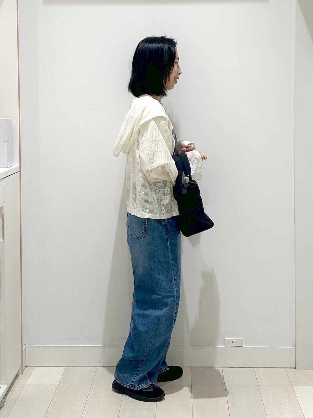 ブラック系のトートバッグ、ブルー系のデニムパンツ、ベージュ系のパーカーを着用したレディースの春コーディネートの4枚目の写真