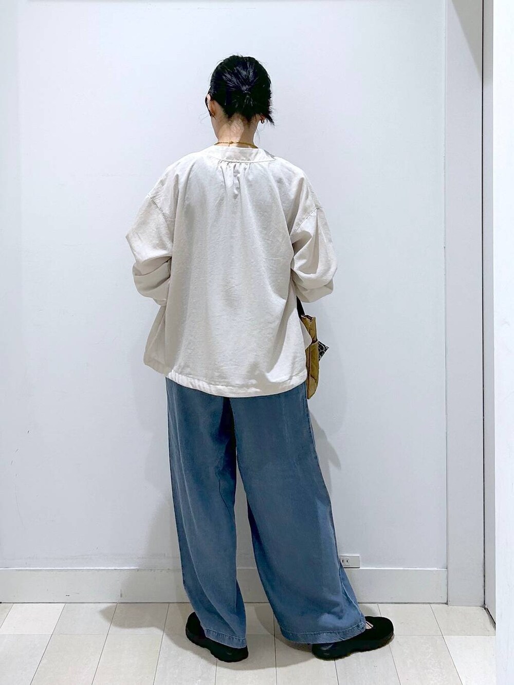 ブラウン系のトートバッグ、グレー系のタンクトップ、ベージュ系のブルゾンを着用したレディースの春コーディネートの3枚目の写真