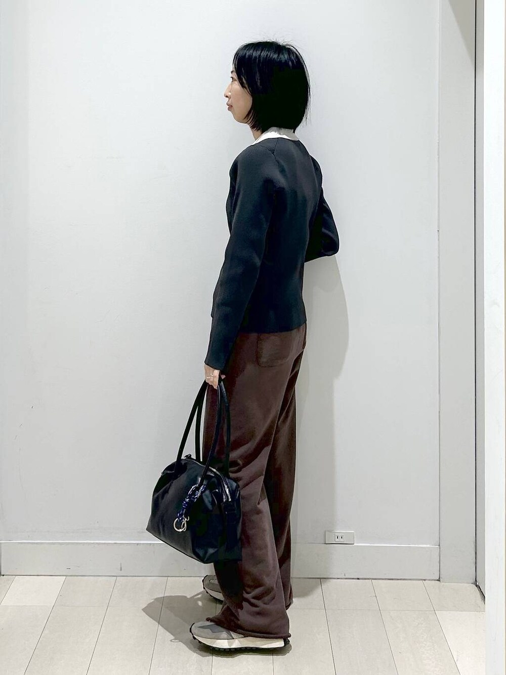 ブラック系のボストンバッグ、グレー系のニット/セーター、ブラウン系のスウェットパンツを着用したレディースの冬コーディネートの2枚目の写真