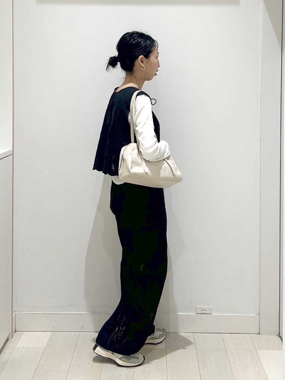 ブラック系のベスト、ブラック系のその他パンツ、ベージュ系のショルダーバッグを着用したレディースの春コーディネートの4枚目の写真