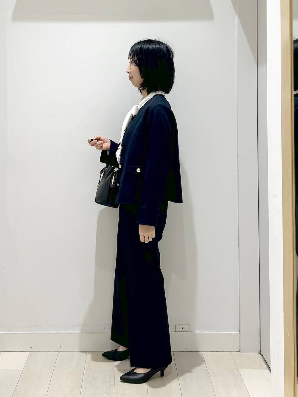 ホワイト系のショルダーバッグ、ブラック系のパンプス、ブルー系のスラックスを着用したレディースの冬コーディネートの2枚目の写真