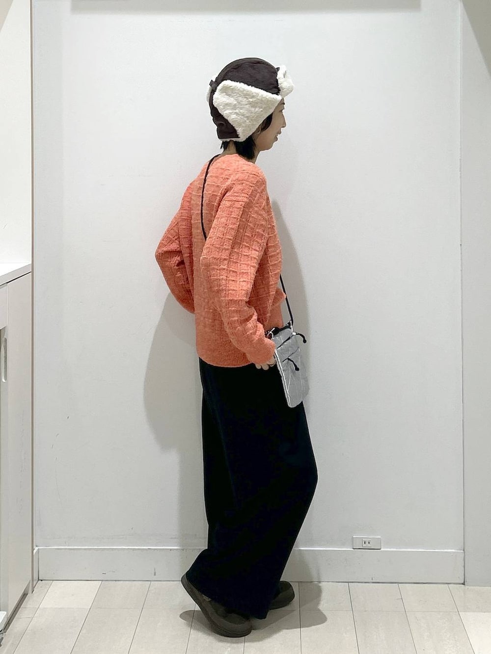 オレンジ系のニット/セーター、ブラック系のその他パンツ、グレー系のショルダーバッグを着用したレディースの冬コーディネートの2枚目の写真