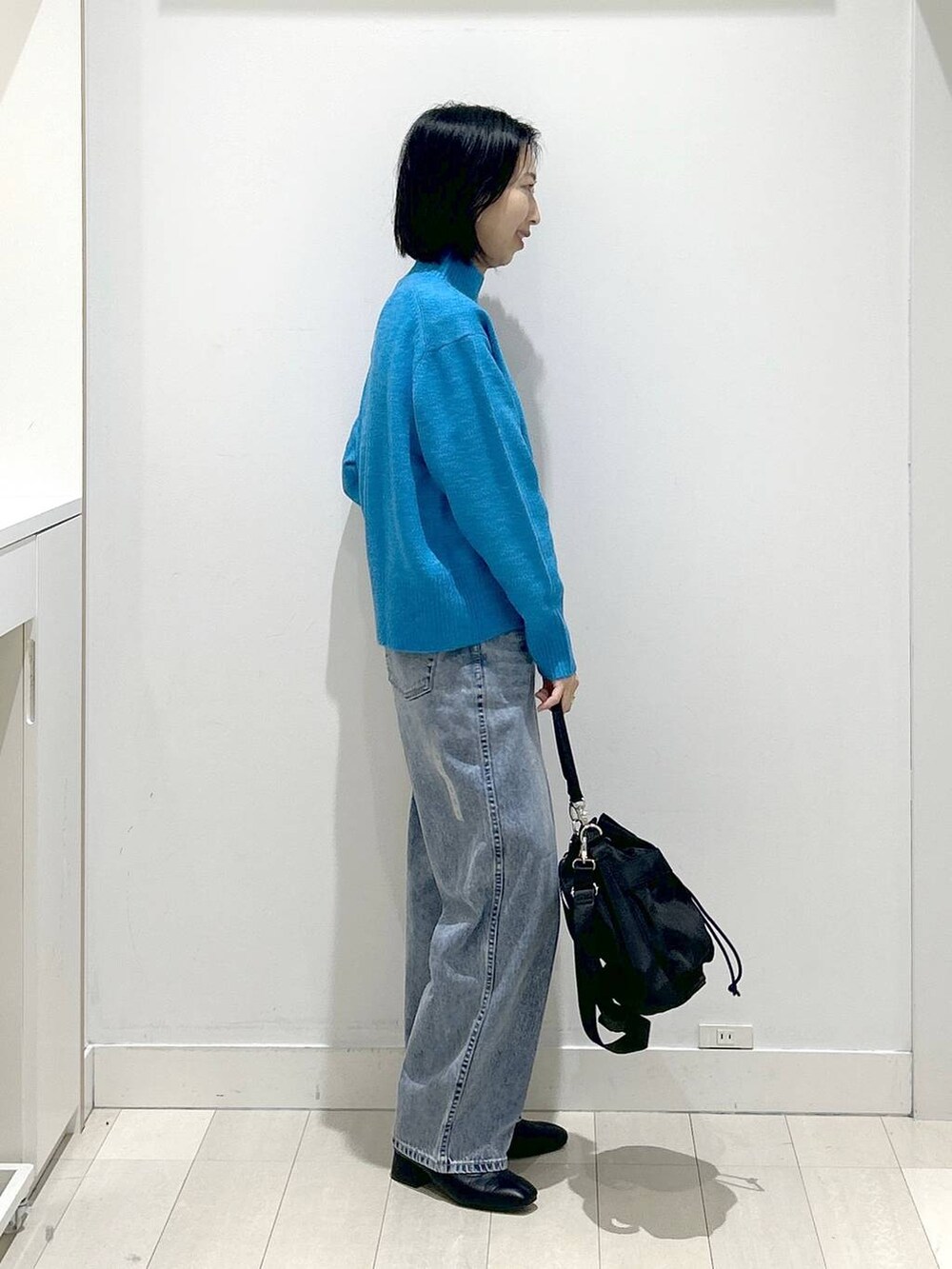 ブラック系のショルダーバッグ、ブルー系のデニムパンツ、ブラック系のブーツを着用したレディースの冬コーディネートの2枚目の写真