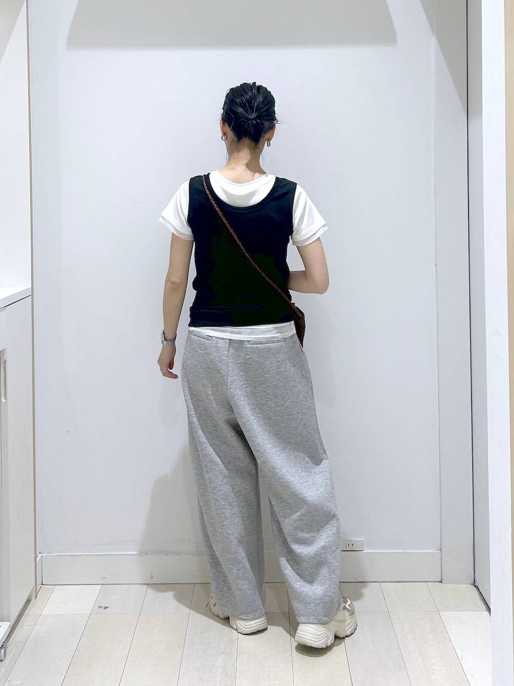 ブラック系のタンクトップ、ブラウン系のクラッチバッグ、グレー系のその他パンツを着用したレディースの春コーディネートの3枚目の写真