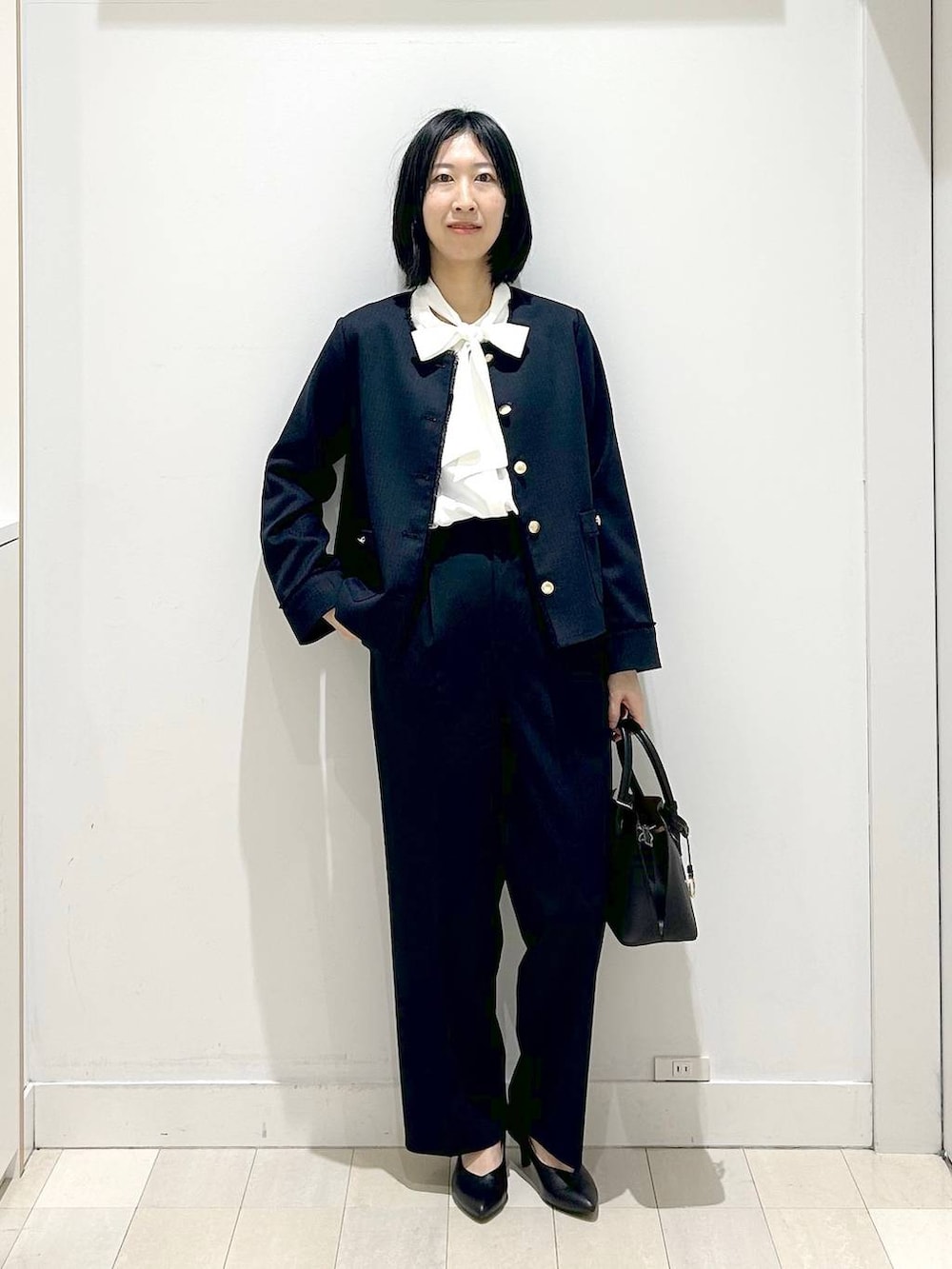 ホワイト系のショルダーバッグ、ブラック系のパンプス、ブルー系のスラックスを着用したレディースの冬コーディネートの5枚目の写真