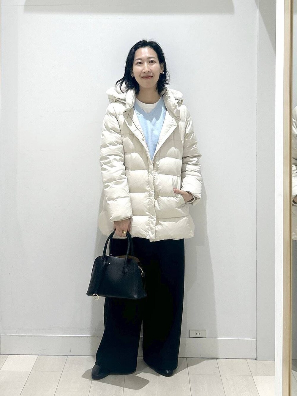 ブラック系のショルダーバッグ、ベージュ系のダウンジャケット/コート、ホワイト系のTシャツ/カットソーを着用したレディースの冬コーディネートの5枚目の写真