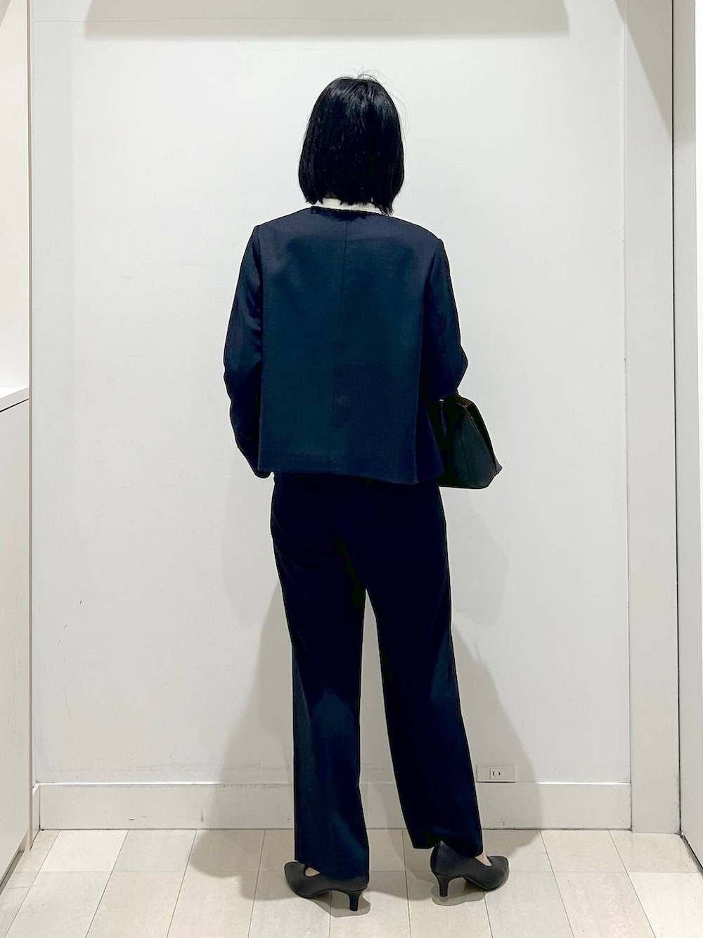 ホワイト系のショルダーバッグ、ブラック系のパンプス、ブルー系のスラックスを着用したレディースの冬コーディネートの3枚目の写真