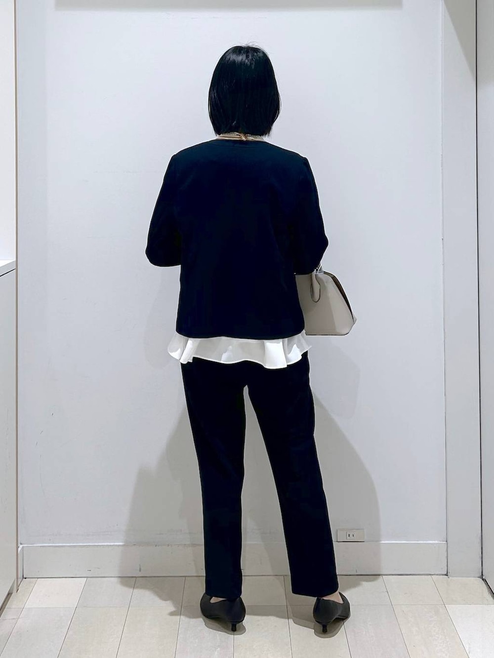 ホワイト系のショルダーバッグ、ブルー系のセットアップ、ブラック系のパンプスを着用したレディースの冬コーディネートの3枚目の写真