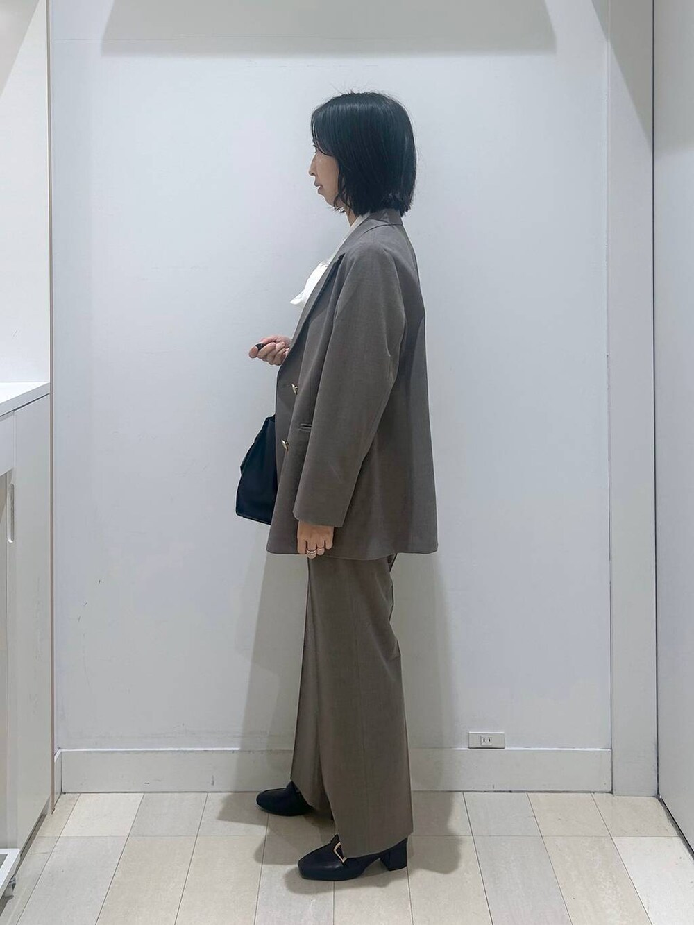 ブラック系のローファー、ブラウン系のスラックス、ホワイト系のシャツ/ブラウスを着用したレディースの冬コーディネートの2枚目の写真