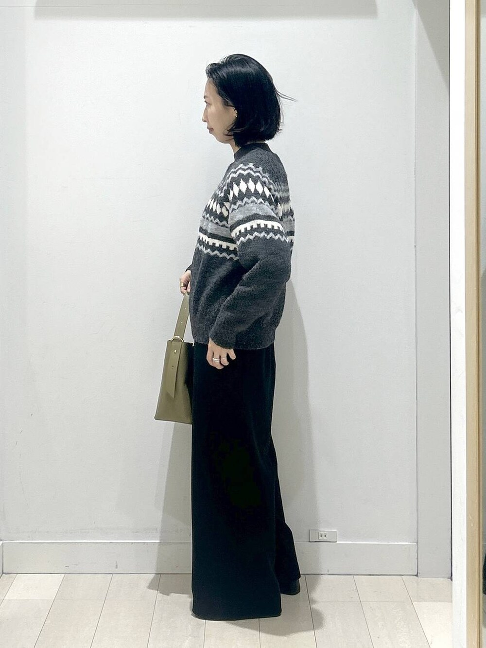 グリーン系のショルダーバッグ、グレー系のニット/セーター、ブラック系のその他パンツを着用したレディースの冬コーディネートの4枚目の写真