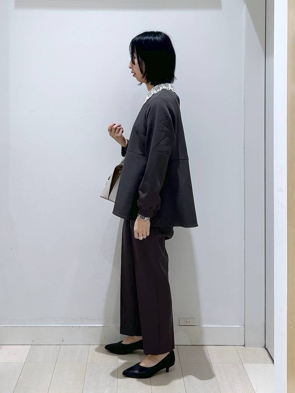 ホワイト系のショルダーバッグ、グレー系のセットアップ、ブラック系のパンプスを着用したレディースの冬コーディネートの4枚目の写真