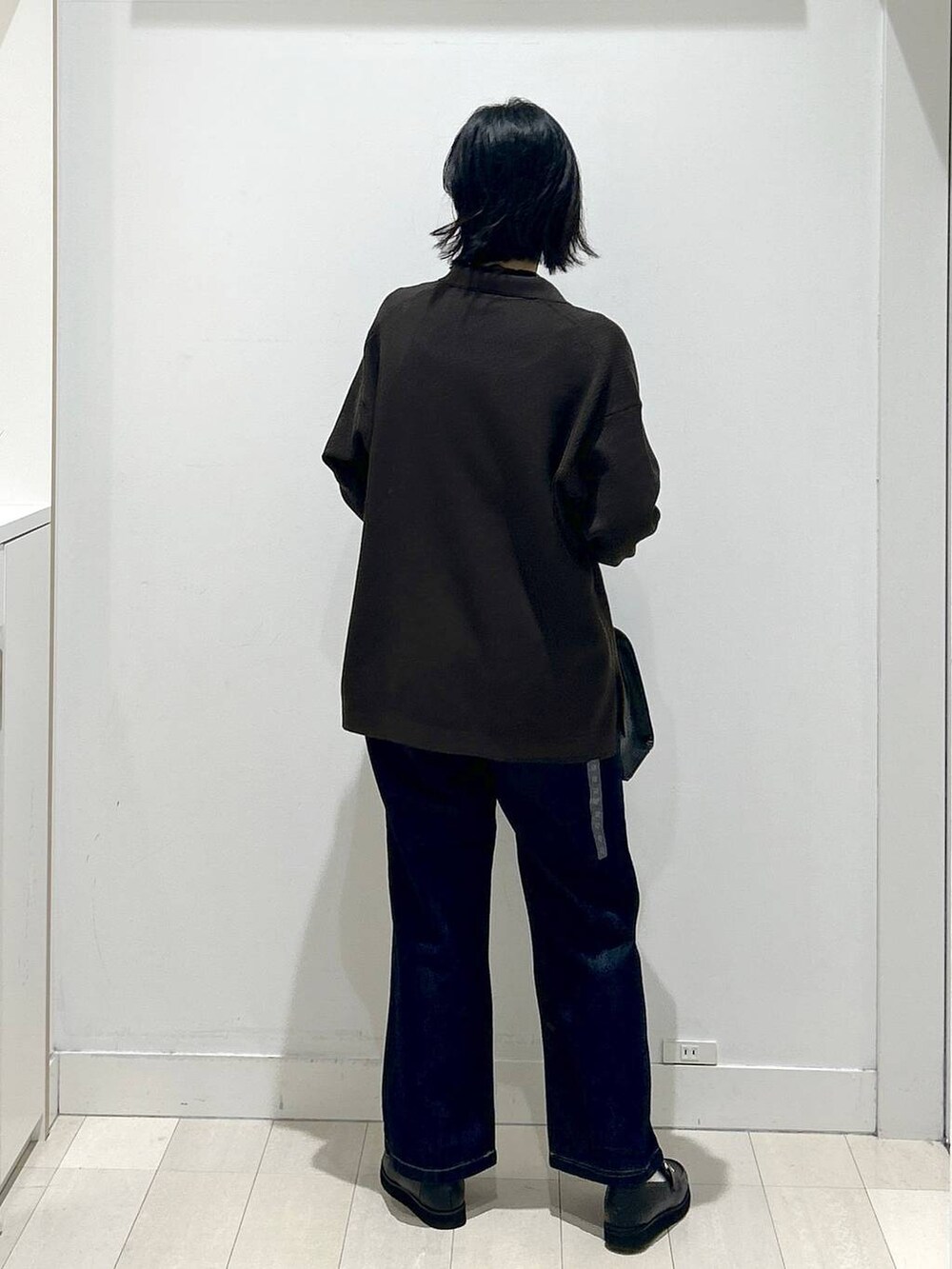 ブラック系のローファー、ブルー系のデニムパンツ、ブラック系のショルダーバッグを着用したレディースの秋コーディネートの3枚目の写真