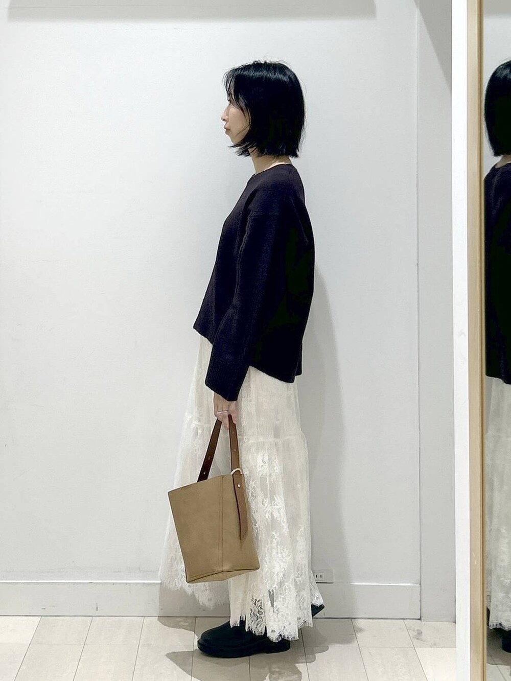 ブラウン系のショルダーバッグ、ブラック系のブーツ、ブラウン系のワンピースを着用したレディースの冬コーディネートの4枚目の写真