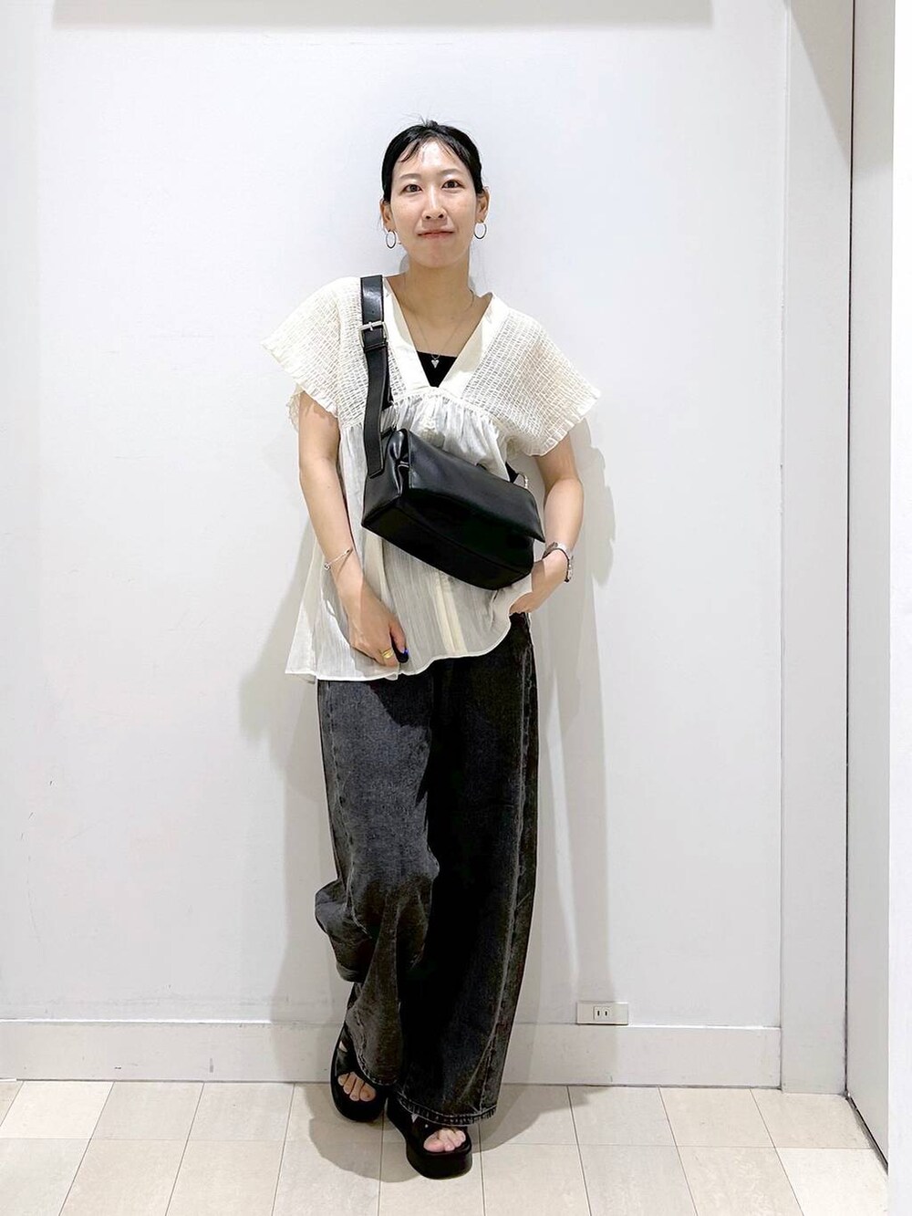 ブラック系のデニムパンツ、ベージュ系のシャツ/ブラウス、ブラック系のサンダルを着用したレディースの夏コーディネートの5枚目の写真