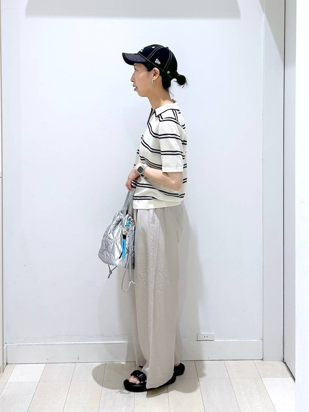 シルバー系のハンドバッグ、ベージュ系のその他パンツ、ホワイト系のニット/セーターを着用したレディースの春コーディネートの2枚目の写真