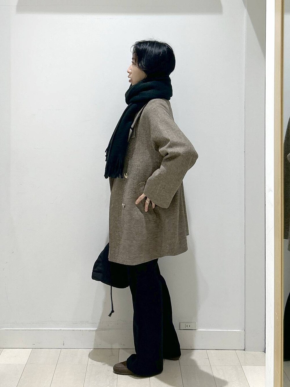 ブラウン系のチェスターコート、ブラック系のハンドバッグ、ブラウン系のニット/セーターを着用したレディースの冬コーディネートの4枚目の写真