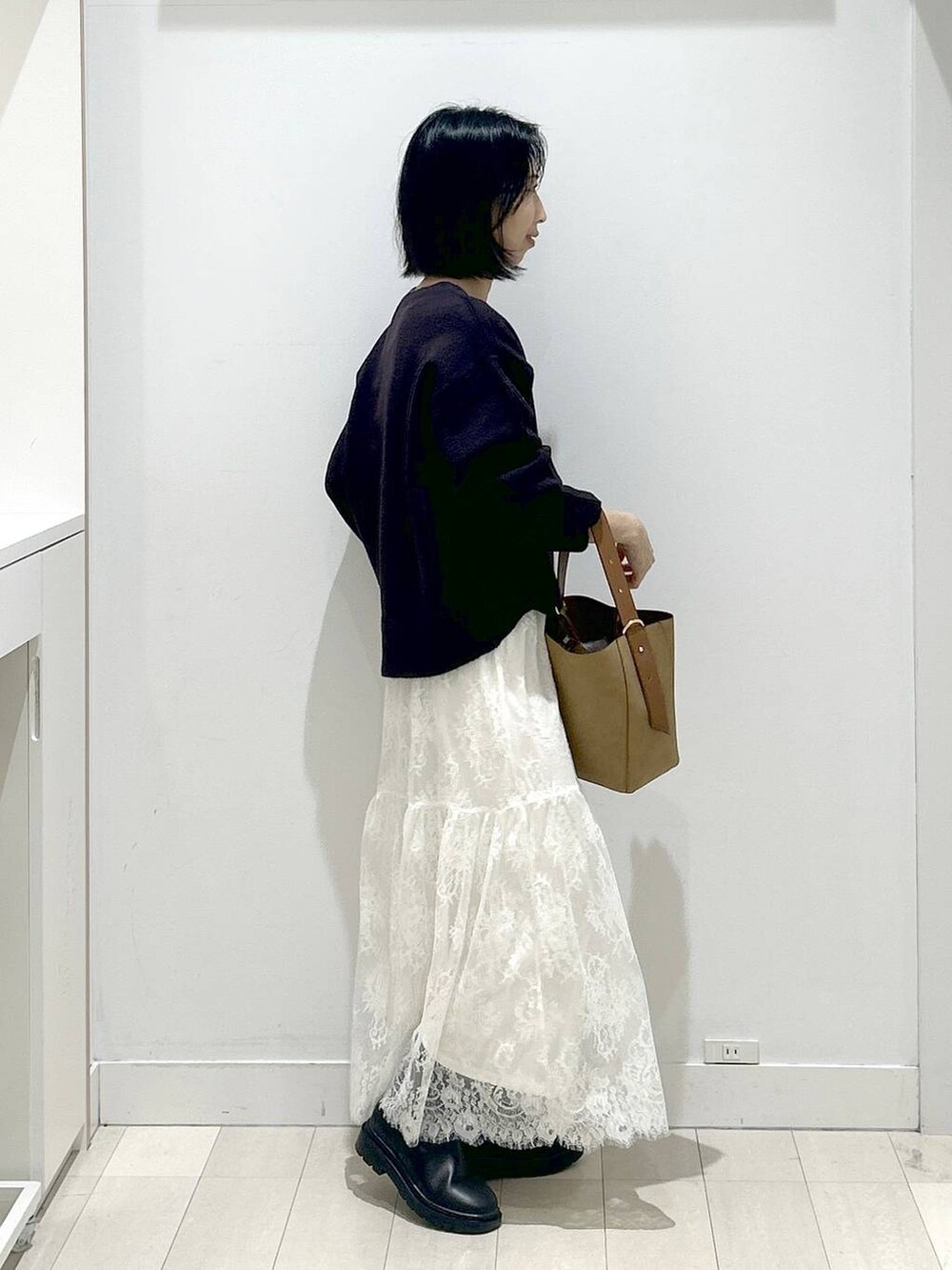 ブラウン系のショルダーバッグ、ブラック系のブーツ、ブラウン系のワンピースを着用したレディースの冬コーディネートの2枚目の写真