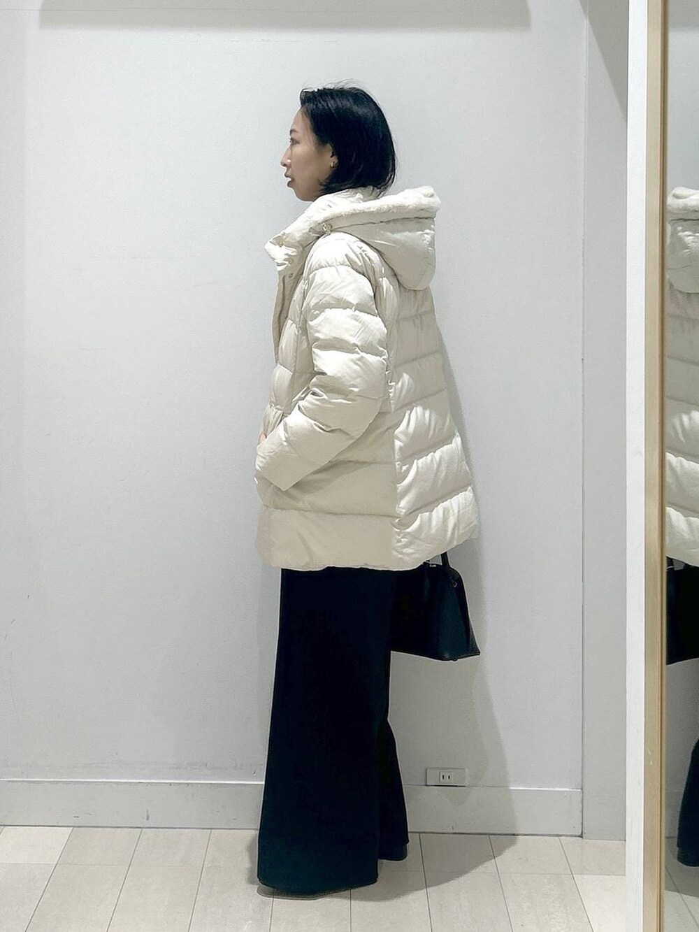 ブラック系のショルダーバッグ、ベージュ系のダウンジャケット/コート、ホワイト系のTシャツ/カットソーを着用したレディースの冬コーディネートの4枚目の写真