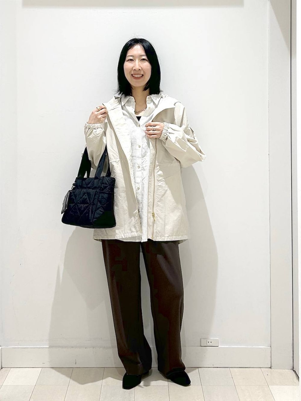 ブラック系のトートバッグ、ベージュ系のパーカー、ブラウン系のその他パンツを着用したレディースの春コーディネートの5枚目の写真