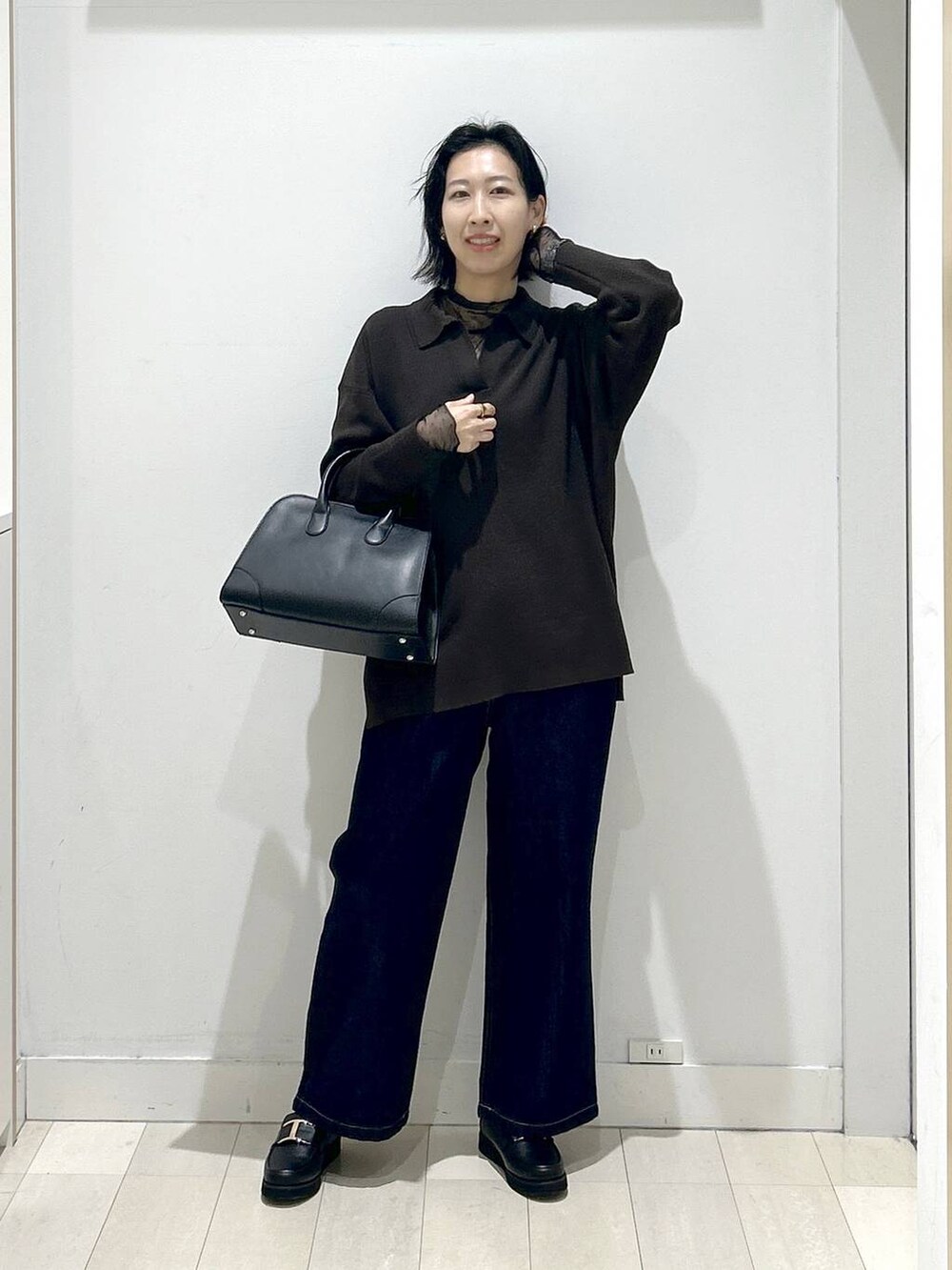 ブラック系のローファー、ブルー系のデニムパンツ、ブラック系のショルダーバッグを着用したレディースの秋コーディネートの5枚目の写真